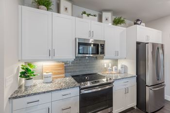 A kitchen with white cabinets and a granite countertop.